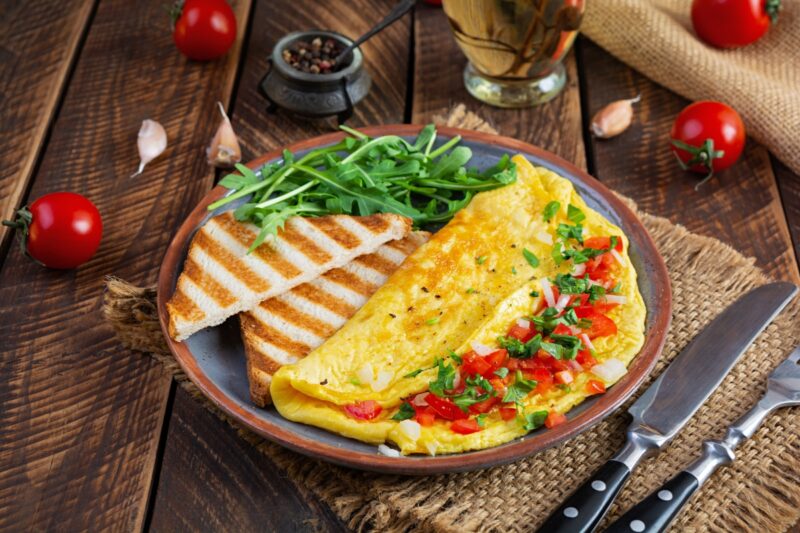 prikaz serviranog omleta sa povrćem i istostiranim hlebom na tanjiru